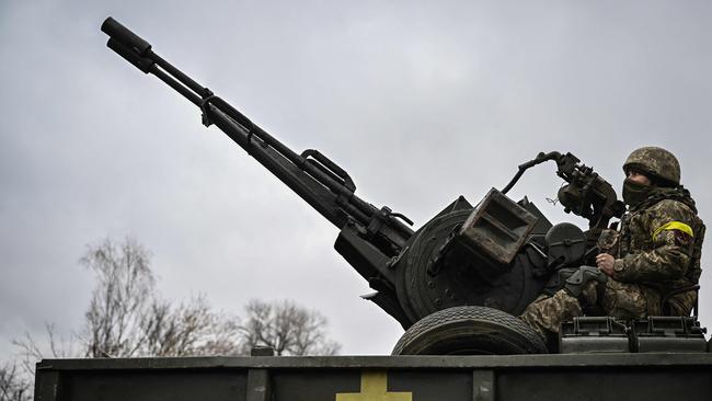 A Ukrainian soldier keeps position sitting on an anti-aircraft gun at a frontline, northeast of Kyiv. Picture: Aris Messinis / AFP