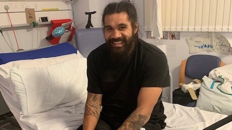 Mose Masoe sits up in his hospital bed