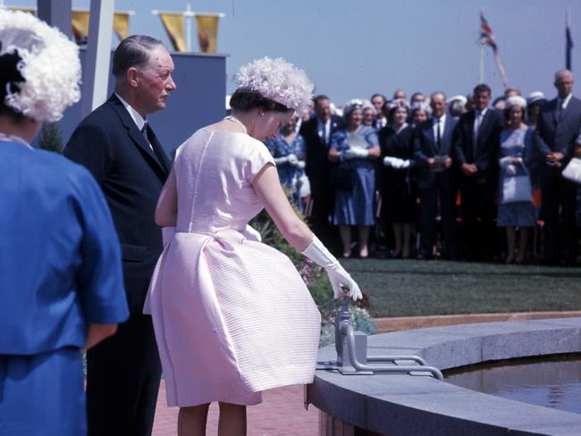 Queen Elizabeth II turns a gold tap to start a commemorative fountain by Geoffrey Shedley.