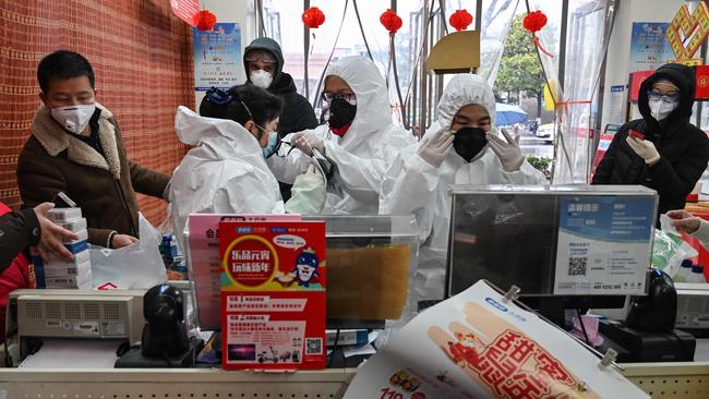 Pharmacy workers don protective clothes and masks to serve customers in Wuhan. Picture: Hector Retamal