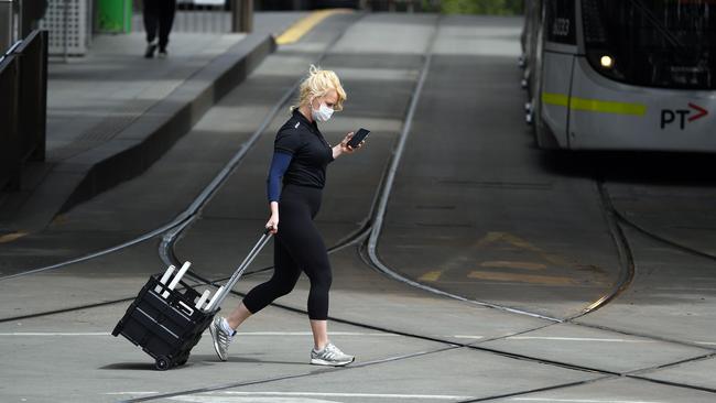 A woman crosses a quiet street in Melbourne on Sunday. Picture: AFP