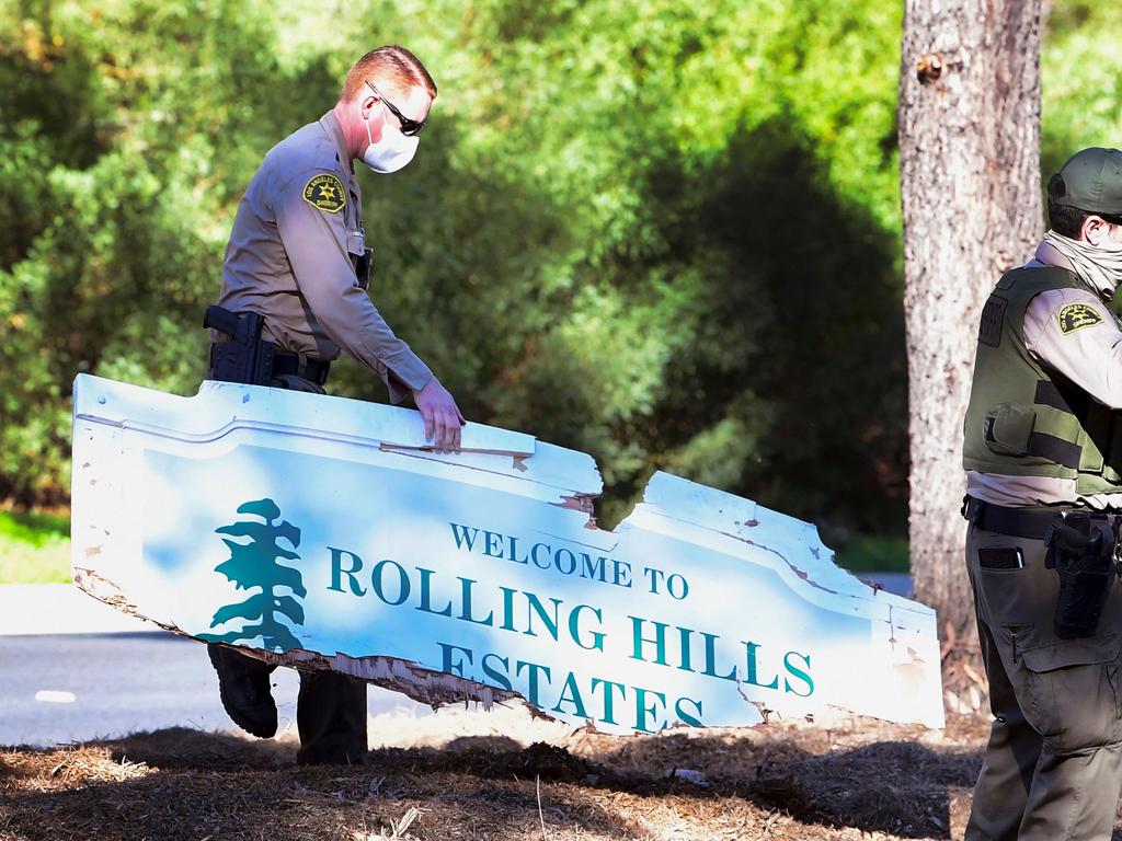 A Los Angeles County sheriffs department officer carries a broken "Welcome to Rolling Hills Estates" sign destroyed from the vehicle driven by golfer Tiger Woods. (Photo by Frederic J. BROWN / AFP)