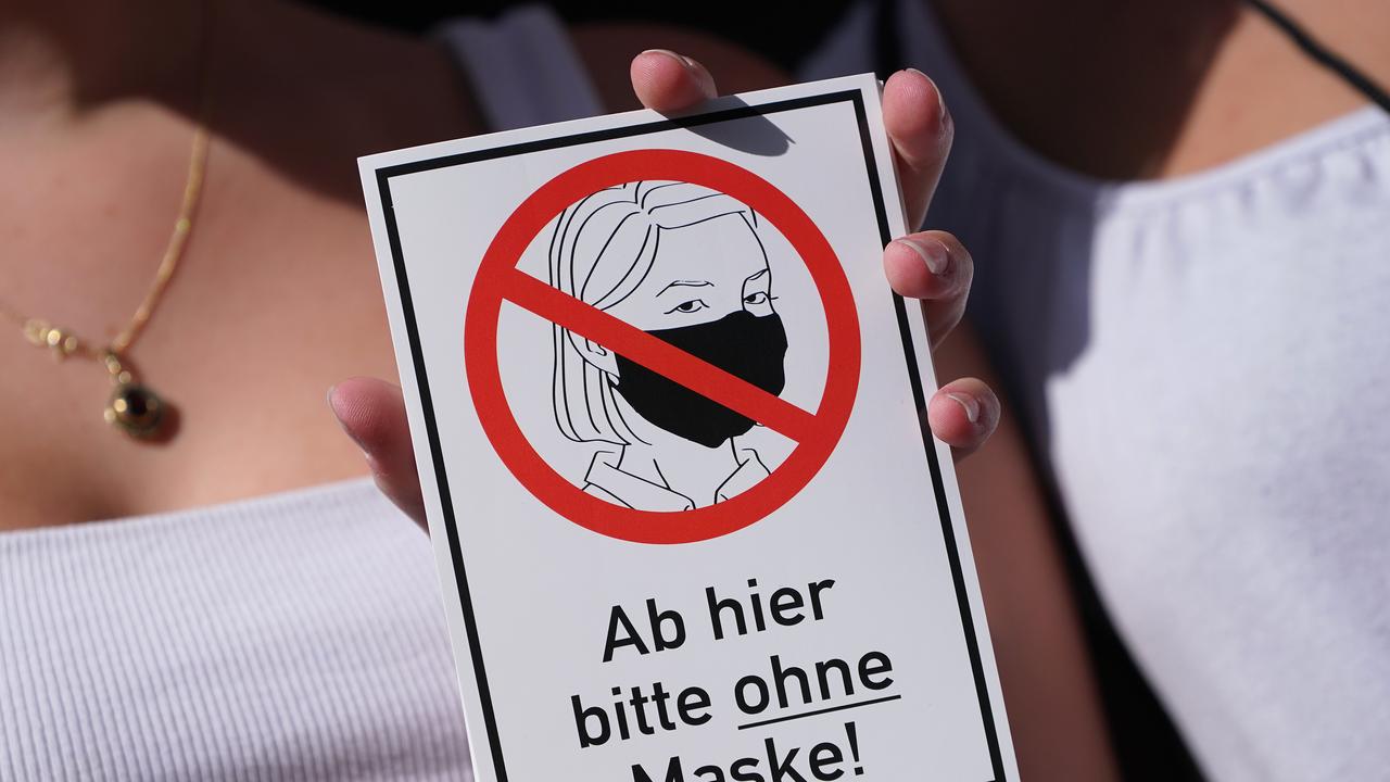 Two women hold up stickers that read: "From here on please without a mask!" as they march with coronavirus sceptics, right-wing extremists and others in protest against coronavirus-related restrictions and government policy in Berlin.