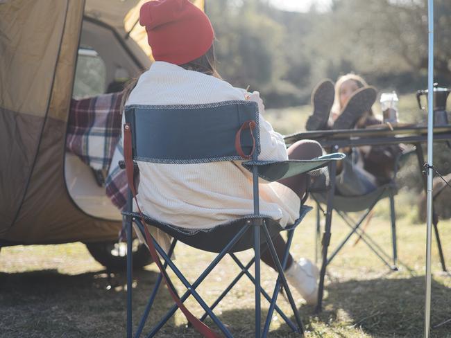 Happy couple sitting drinking coffee at sunrise. Young people having fun on winter vacations traveling around the world. Concept of travel, love, van lifestyle and freedom.
