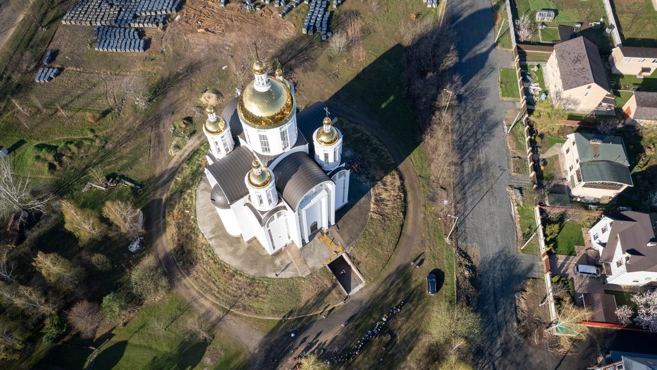 As seen from an aerial view, people gather in front of the Church of St. Andrews. The church grounds were the site of mass graves (top) of people killed during the Russian occupation of the town. Picture: John Moore/Getty Images