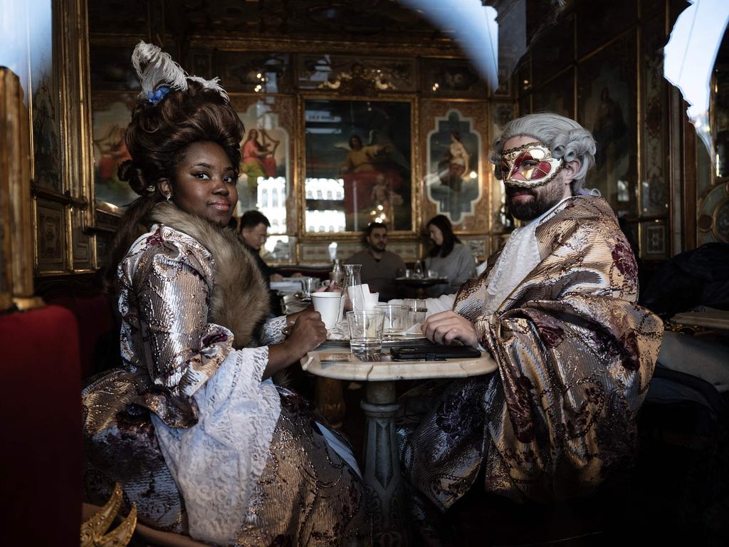 Participants wearing carnival costumes sit in the Caffe Florian during the carnival parade at St. Mark Square in Venice. Picture: Marco Bertorello/AFP