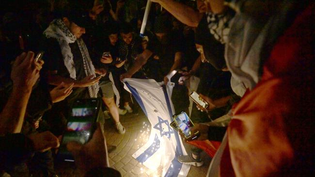 Pro-Palestinian protesters burn the Israeli flag on the forecourt of The Sydney Opera House.