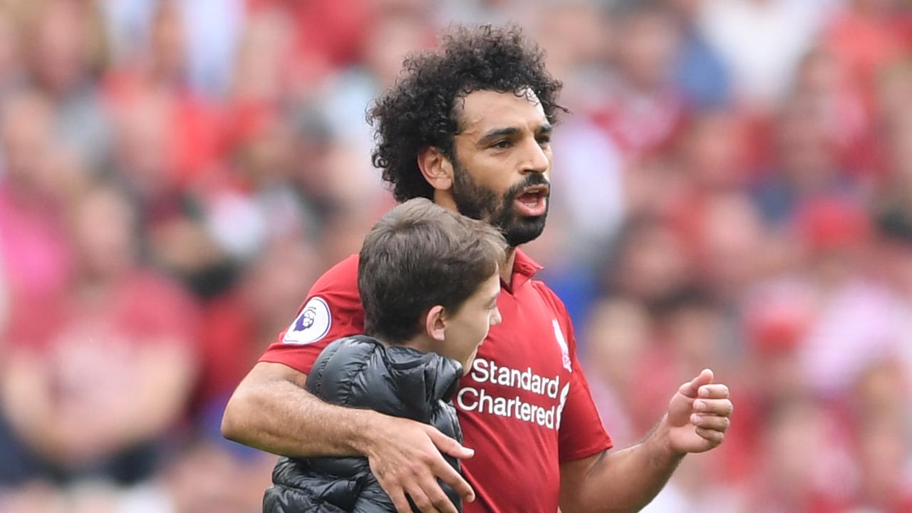 A young fan runs onto the pitch and embraces Mohamed Salah.