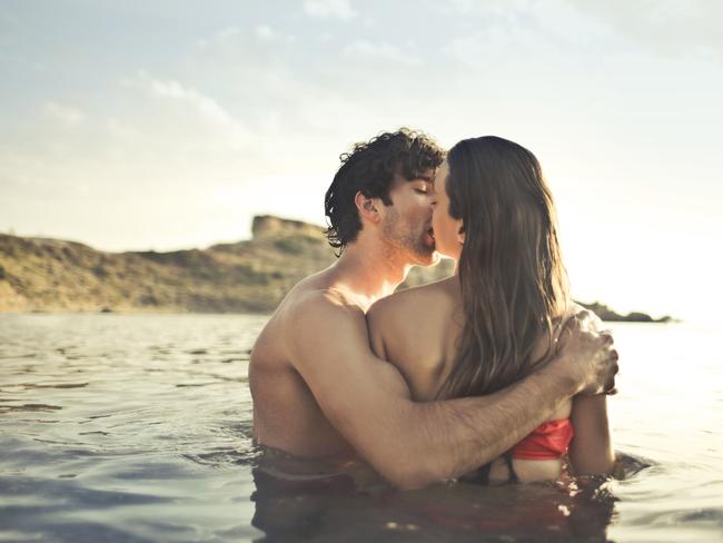 Couple of lovers in the water at the seaside kissing intensely