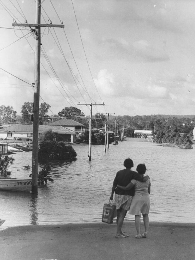 Women look at a flooded Jindalee.