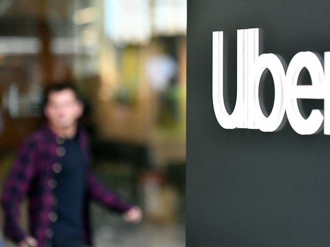 (FILES) In this file photo taken on May 8, 2019 An Uber logo is seen on a sign outside the company's headquarters location as people protest nearby in San Francisco, California. - California voters put the brakes November 3 on a law stopping ride share firms such as Uber and Lyft from classifying drivers as independent contractors, according to US media. (Photo by Josh Edelson / AFP)