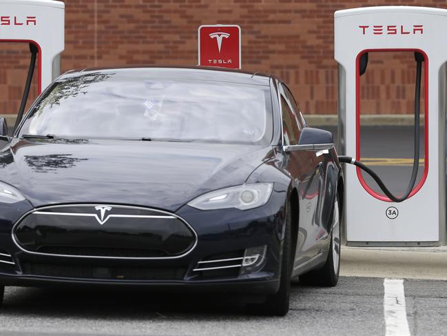 FILE - In this Saturday, June 24, 2017, file photo, a Tesla car recharges at a charging station at Cochran Commons shopping center in Charlotte, N.C. On Monday, Sept. 11, 2017, Tesla Inc. announced that more charging stations are on the way. The stations will be installed at places such as supermarkets and shopping centers, and in cities like Chicago and Boston. (AP Photo/Chuck Burton, File)
