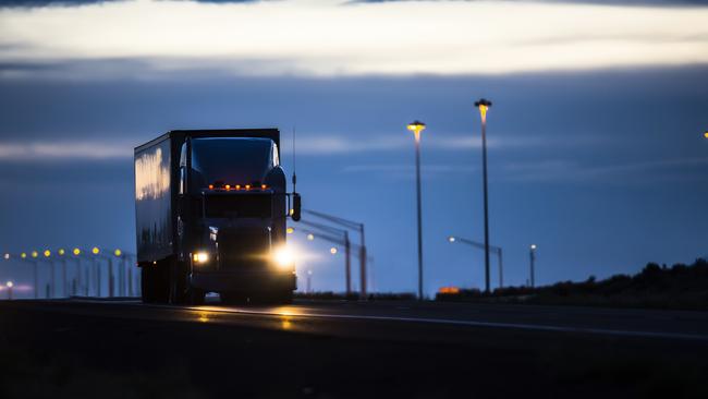 A semi-truck on a highway at night.