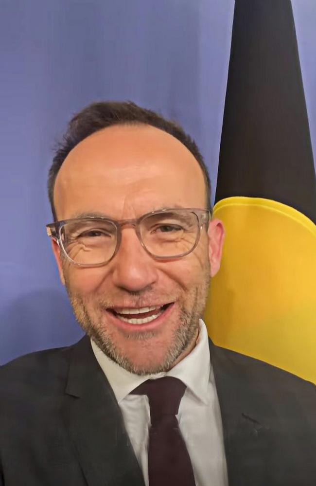 Adam Bandt in front of the Aboriginal flag.
