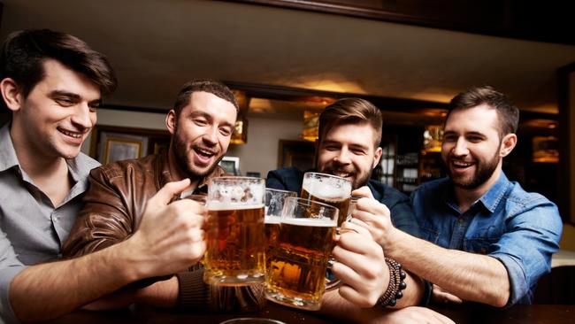 Four cheerful friends toasting with beer at pub