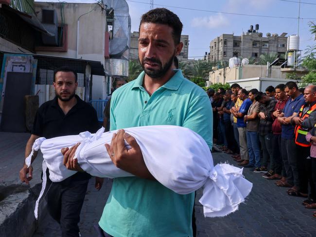 A Palestinian man carries the body of a child killed in Israeli shelling during a funeral in Khan Yunis in the southern Gaza Strip. Picture: AFP