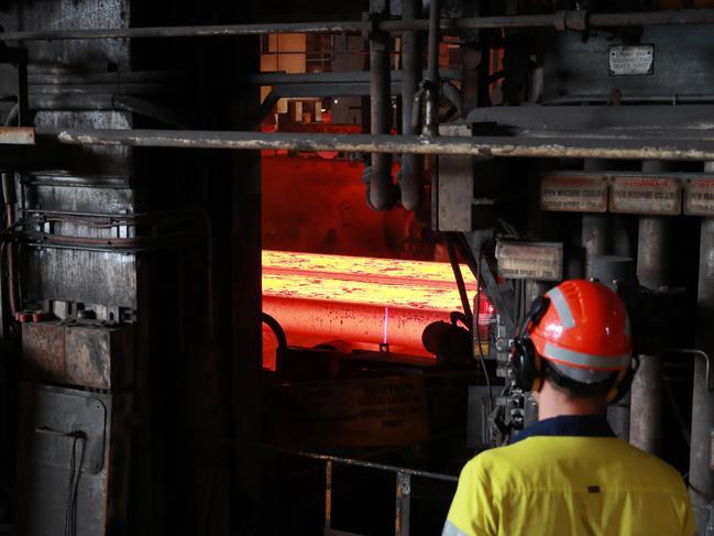 BUDGET2022: A worker watches as slabs of molten metal are cut to length at the Slabcaster at BlueScope Steel manufacturing plant in Port Kembla. John Feder