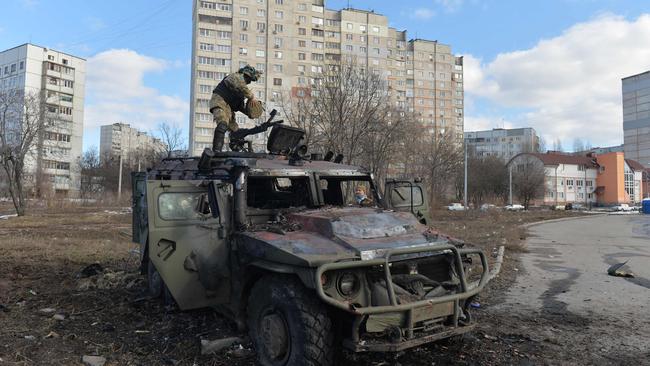 A Ukrainian Territorial Defence fighter examines a destroyed Russian infantry mobility vehicle in Kharkiv. Picture: AFP