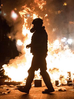 A police officer in riot gear walks past a fire on Interstate 85 during protests in Charlotte, North Carolina. Picture: Getty