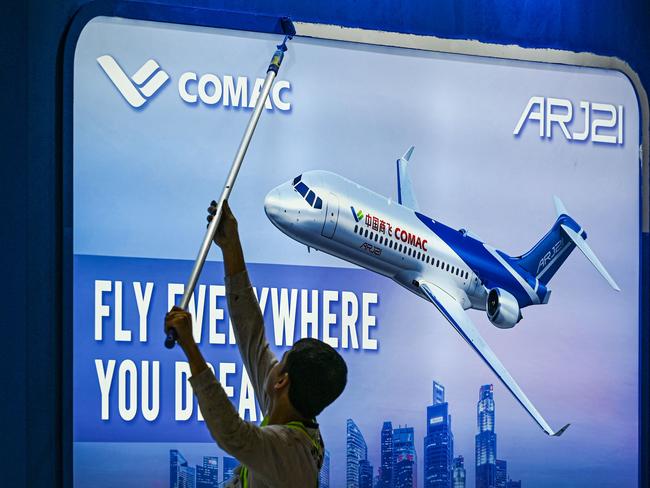 A worker prepares China's Comac booth ahead of the Singapore Airshow in Singapore on February 18, 2024. (Photo by Roslan RAHMAN / AFP)