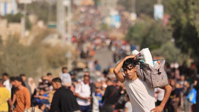 A Palestinian man carries his belongings as families fleeing Gaza City. Picture: MAHMUD HAMS / AFP)