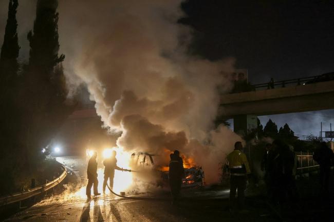 Firefighters extinguish a burning UNIFIL vehicle on the road leading to Beirut's international airport on Friday night