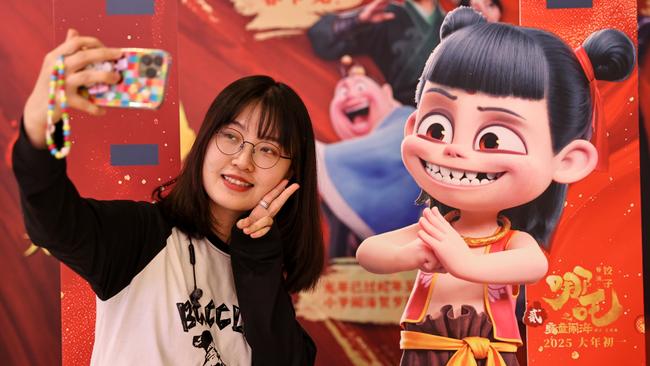 A girl poses for a photo with a Ne Zha 2 poster on February 12, 2025 in Shenyang, China. Picture: Yu Haiyang/China News Service/VCG via Getty Images.