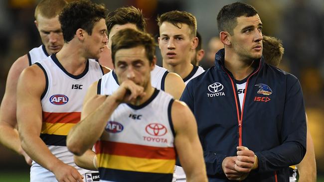 Taylor Walker leads the Crows from the field after losing to Hawthorn.