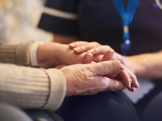 A female nurse consoles a senior patient at home, aged care generic