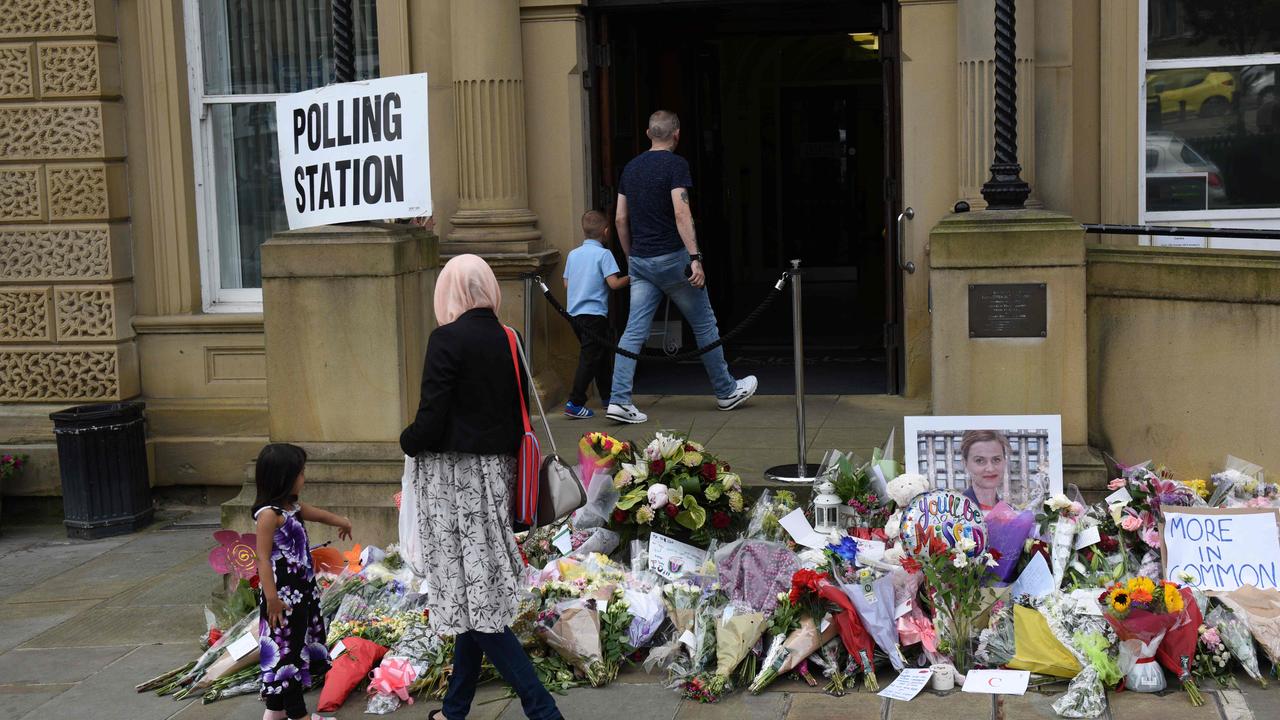 TOPSHOT - People pass floral tributes to murdered MP Jo Cox outside Batley Town Hall as they arrive to vote in the EU referendum in Batley, northern England on June 23, 2016.    Millions of Britons began voting today in a bitterly-fought, knife-edge referendum that could tear up the island nation's EU membership and spark the greatest emergency of the bloc's 60-year history. / AFP PHOTO / OLI SCARFF