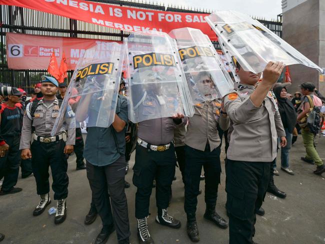 Policemen form a barricade with their shields as parliament members attempt to meet with people who gathered near the Parliament building in Jakarta on August 22, 2024 to protest a move to reverse the Constitutional Court's decision altering eligibility rules for candidates in a key election later this year. (Photo by BAY ISMOYO / AFP)