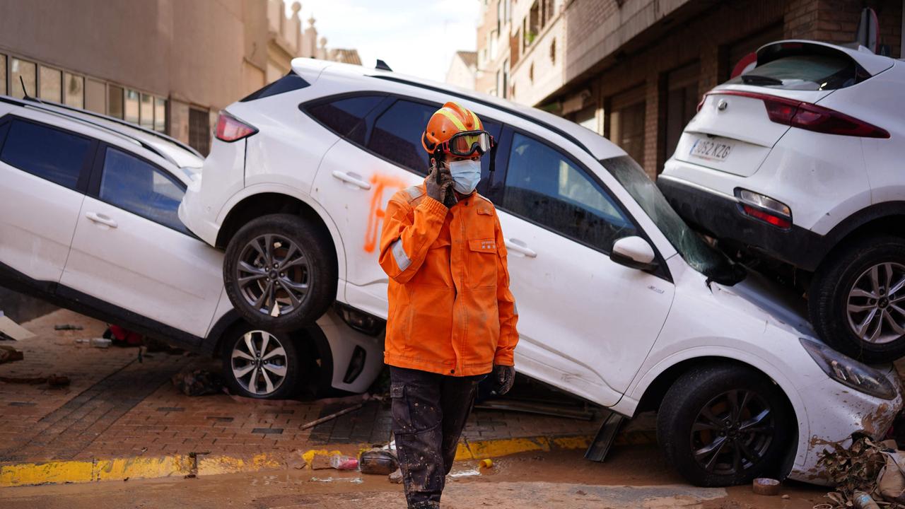 A Civil Protection member walks past another pile up of flood-damaged vehicles in Sedavi. Picture: Manaure Quintero/AFP