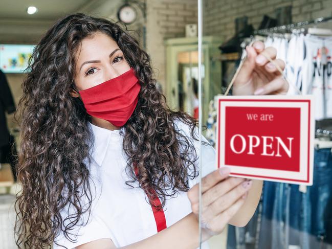 Happy business owner hanging an open sign during COVID-19