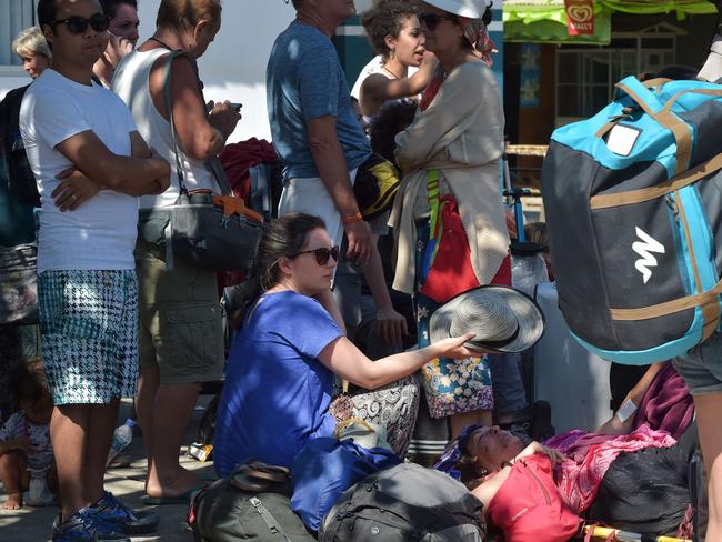 An injured Italian tourist (centre R) is shaded by another as they wait for an ambulance after locals and tourists were evacuated from the Gili islands north of Lombok. Picture: AP