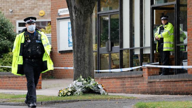 Police officers look on near the bunches of flowers layed by British Prime Minister Boris Johnson, Labour Party leader Keir Starmer, Speaker of the House Lindsay Hoyle and Home Secretary Priti Patel at the scene of the fatal stabbing of David Amess, at Belfairs Methodist Church in Leigh-on-Sea. Picture: AFP