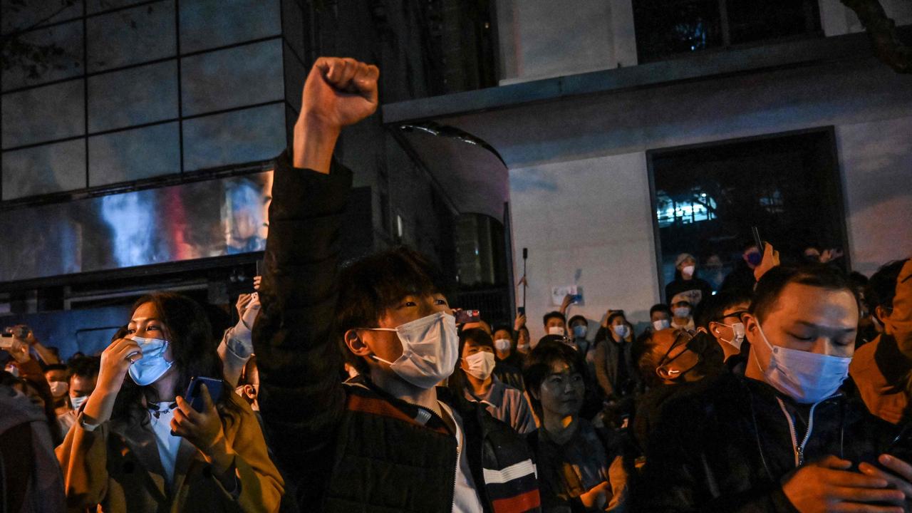 Protesters sing slogans while gathering on a street in Shanghai. (Photo by Hector RETAMAL / AFP)