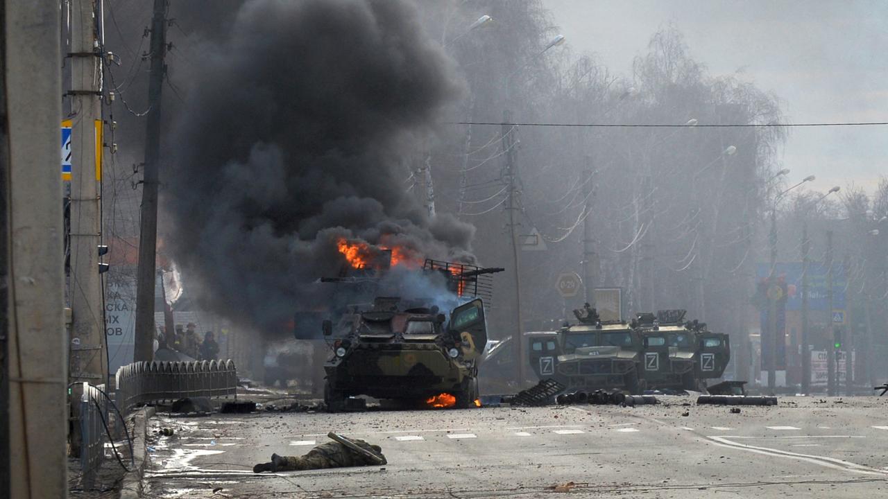 A Russian Armoured personnel carrier (APC) burns next to unidentified soldier's body during a fight with the Ukrainian armed forces in Kharkiv. (Photo by Sergey BOBOK / AFP)