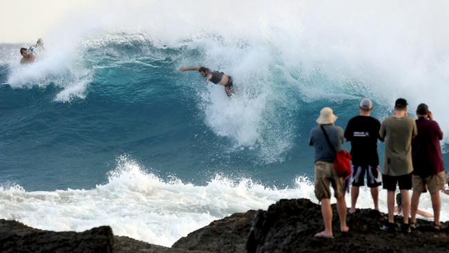 Photographers take pictures of a surfer at Snapper Rocks on the Gold Coast, Thursday February 21, 2019. Huge swells and high tides are set to pummelling southeast Queensland beaches over the coming days as Cyclone Oma tracks towards the Queensland coast. (AAP Image/Dave Hunt)