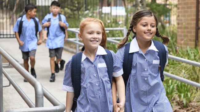 Female primary school students wearing blue gingham dresses with boys in background