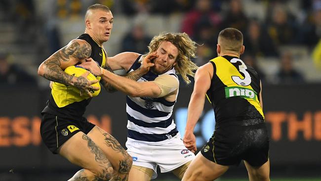 Dustin Martin of the Tigers fends off a tackle by Cameron Guthrie