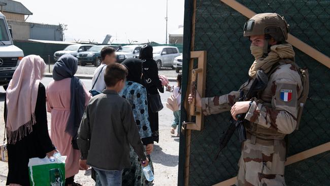 A French soldier watches as refugees board a A400M Atlas military transport aircraft at Kabul airport. Picture: AFP