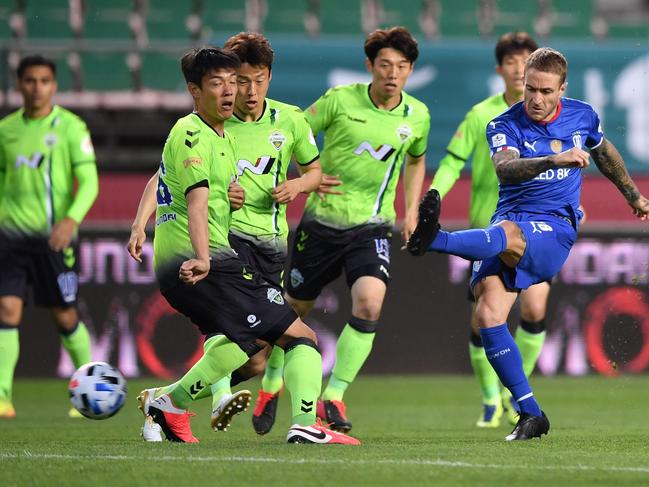 Suwon Samsung Bluewings' Adam Taggart (R) shoots the ball against Jeonbuk Hyundai Motors during the opening game of South Korea's K-League football match at Jeonju World Cup Stadium in Jeonju on May 8, 2020. - The towering stands of the 42,477-capacity Jeonju World Cup Stadium stood empty on May 8 as South Korea opened football's post-coronavirus era without fans, but with an unprecedented international TV audience. (Photo by Jung Yeon-je / AFP)