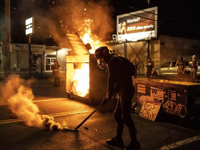 A protester walking past a dumpster fire. Picture: Nathan Howard