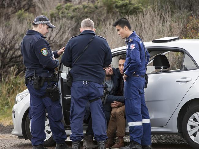 Police and a paramedic talk to two men who were friends with the man who died. Picture: Damian Shaw