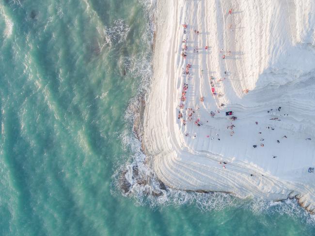 Image Name: The Big MeringuePhotographer Name: Placido  FarandaYear: 2018Image Description: Scala dei Turchi (The Turkish Steps) is a white cliff in Realmonte (Sicily), made of a soft limestone and a blinding white marl. Natural erosion has created steps on the cliff face, making it look soft and sinuous, like a Big Meringue covered with sprinkles (the people sitting and walking on it). The origin of the name “Turkish Steps” is intriguing. While there is a big resemblance to Pamukkale (Turkey), the designation of “Turkish” was given centuries ago by local people, for the frequent raids carried by Turkish pirates on this area. Legend says they would find a shelter for their boats behind this rocky formation, and then climb the “steps” of the cliff and raid the villages. Today, Scala dei Turchi is a wonderful spot for viewing the sunset, as the bright white marl turns into a strong orange. Only after shooting this image, while watching it on a bigger screen, I noticed a newlywed couple in the frame kissing for their wedding photoshoot. Exactly at the edge of the cliff.Copyright: Placido  Faranda, Italy, Entry, Open, Landscape & Nature (2018 Open competition), 2018 Sony World Photography Awards