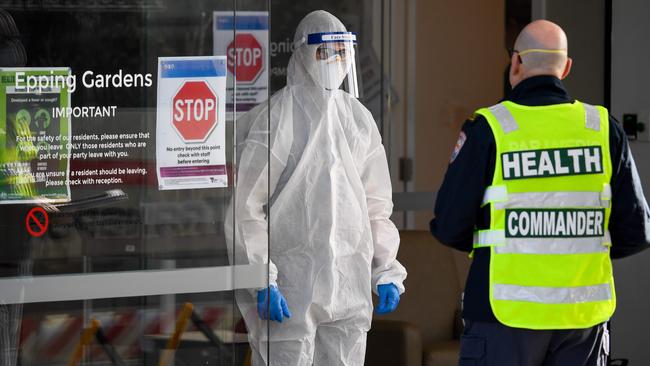 Medical workers speak at the entrance of the Epping Gardens aged care facility. AFP