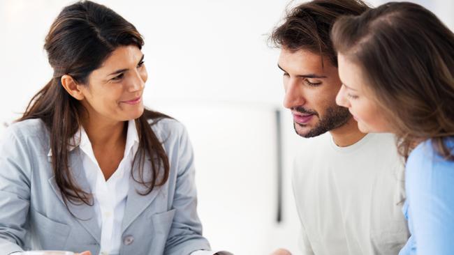 A young couple talking to a mortgage broker about the cost of their home loan. Picture: iStock.