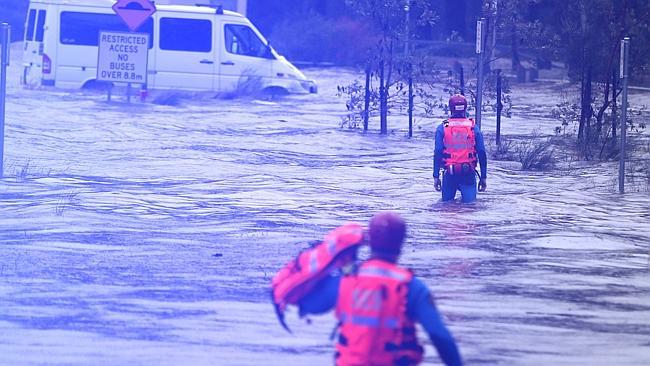 SES crews wade towards an empty car stranded in floodwaters to check it for occupants. Picture: John Grainger