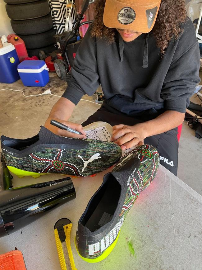 Tyreece Daley putting the finishing touches to his custom-designed footy boots. Photo: Bianca Monaghan