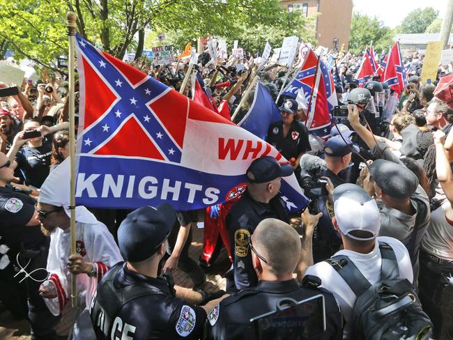 Members of the KKK escorted by police past a large group of protesters during a KKK rally in Charlottesville. Picture: AP